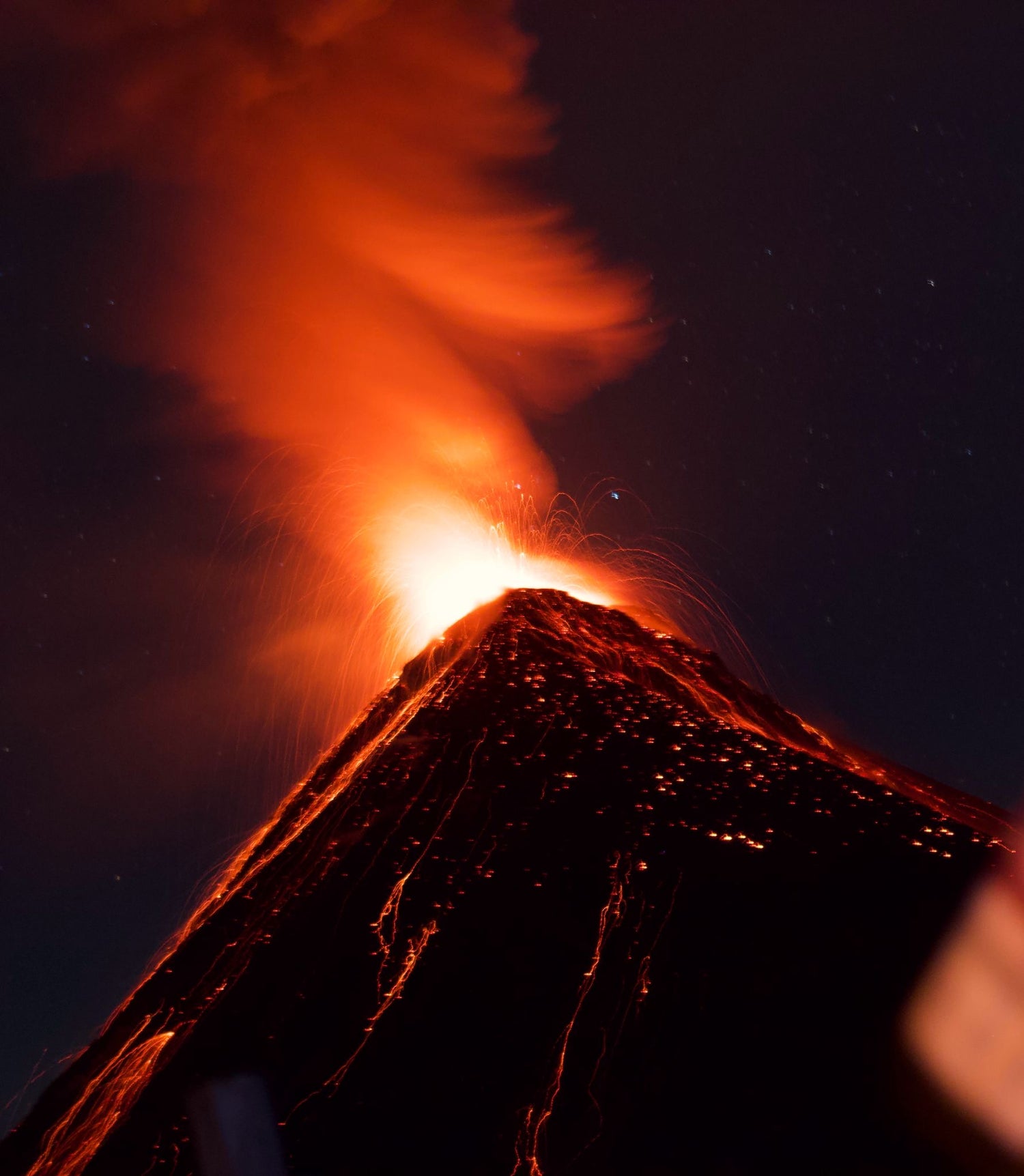 Volcano erupting with bright orange flames against a dark sky. Volcano de fuegoin Guatemala 