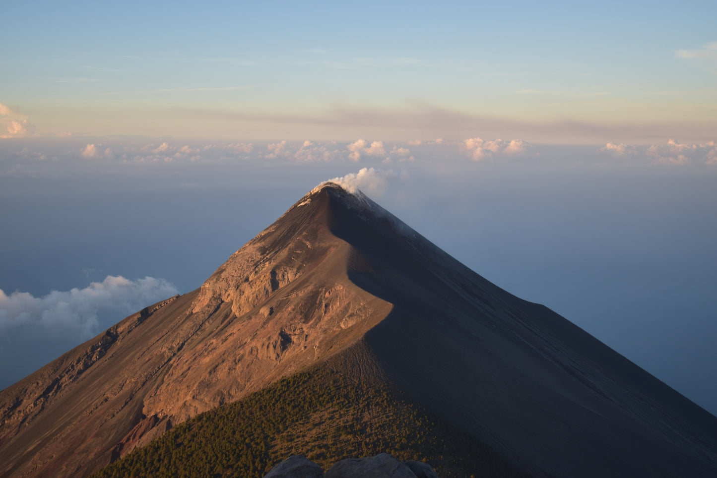 Mountain peak with clouds below during sunset. Volcano de fuego in guatemala